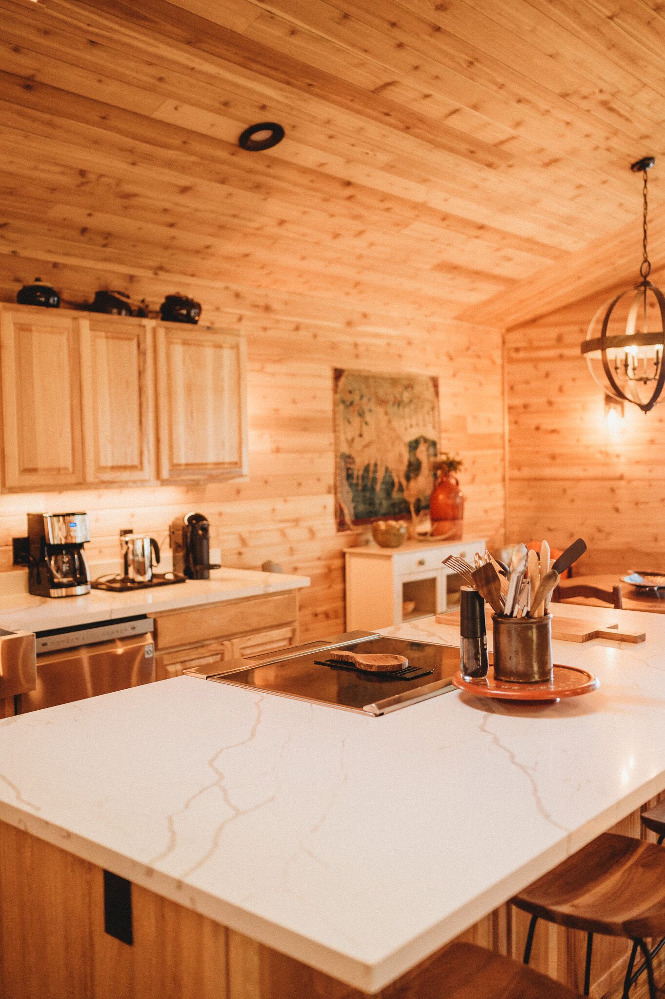 A kitchen with wooden cabinets, a marble countertop, and a hanging light fixture.