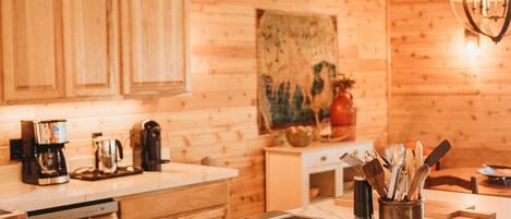 A kitchen with wooden cabinets, a marble countertop, and a hanging light fixture.