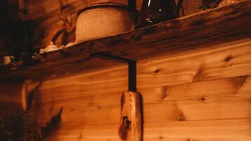 A rustic wooden interior with a large stone sink and a wooden shelf above it.