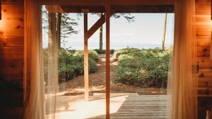 A wooden cabin with a view of a forested path leading to the ocean. - Woodland Bluff (Port Angeles)