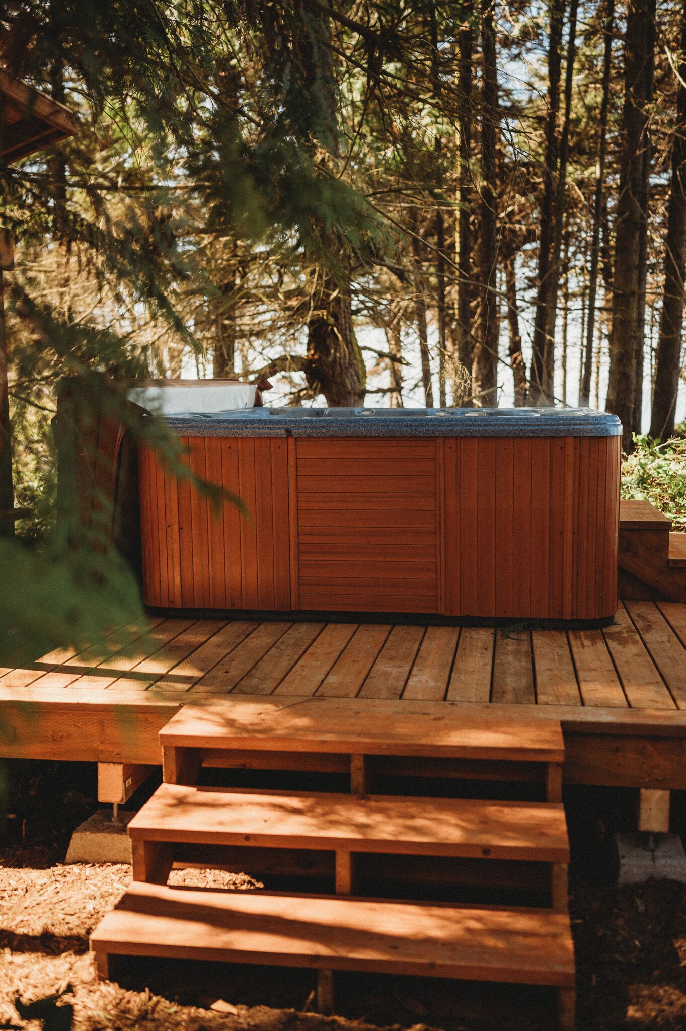 Un jacuzzi en una terraza de madera rodeado de árboles.
