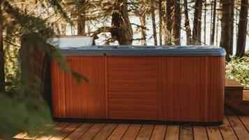 Un jacuzzi en una terraza de madera rodeado de árboles.