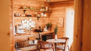 A wooden interior with a dining area, wooden shelves, and a plant. - Woodland Bluff (Port Angeles)