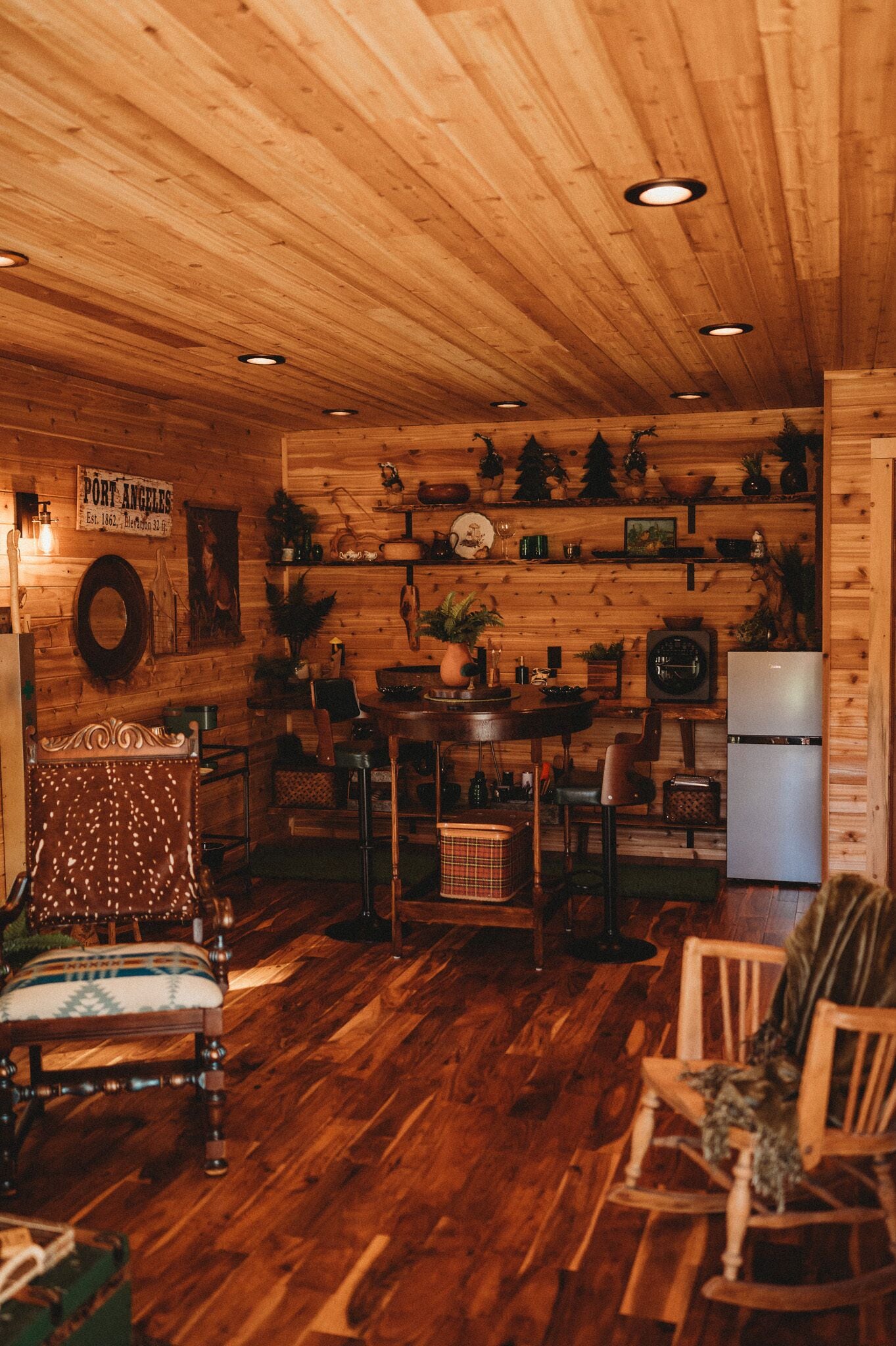 A wooden interior with a dining area, kitchen, and a vintage armchair.