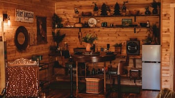 A wooden interior with a dining area, kitchen, and a vintage armchair.