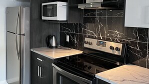 A modern kitchen with stainless steel appliances, dark cabinetry, and a marble backsplash. - Calgary elegant single room &shared bathroom close LRT&free parking (Calgary)