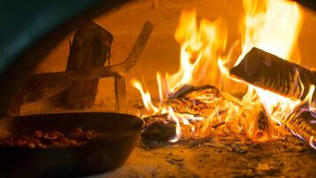 Un forno a legna con ardenti tronchi e una pentola di cibo.