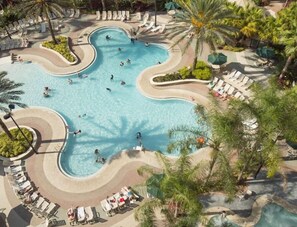 Eine Vogelperspektive zeigt einen Resort-Pool mit mehreren Bereichen, umgeben von Palmen und Liegestühlen.
