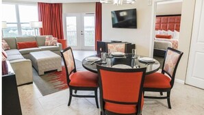 Una sala de estar moderna con un conjunto de sofá, una mesa de comedor con sillas y un televisor de pantalla plana montado en la pared.