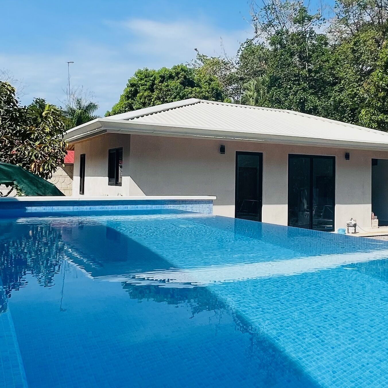 A modern building with a swimming pool, large windows, and a flat roof.