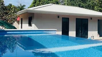 A modern building with a swimming pool, large windows, and a flat roof.
