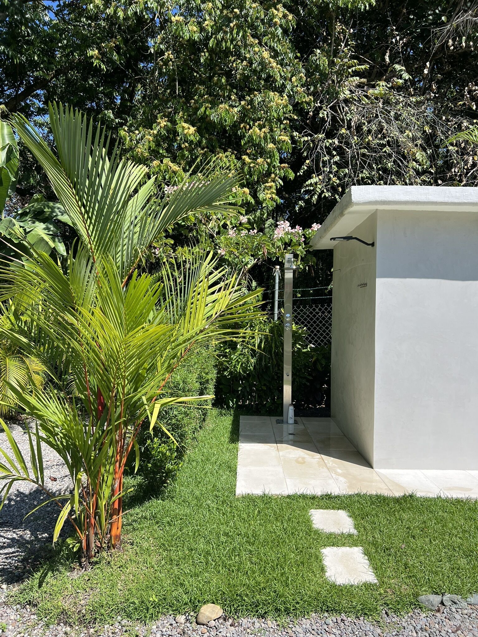 A modern building with a white exterior, surrounded by lush greenery and a well-maintained lawn.