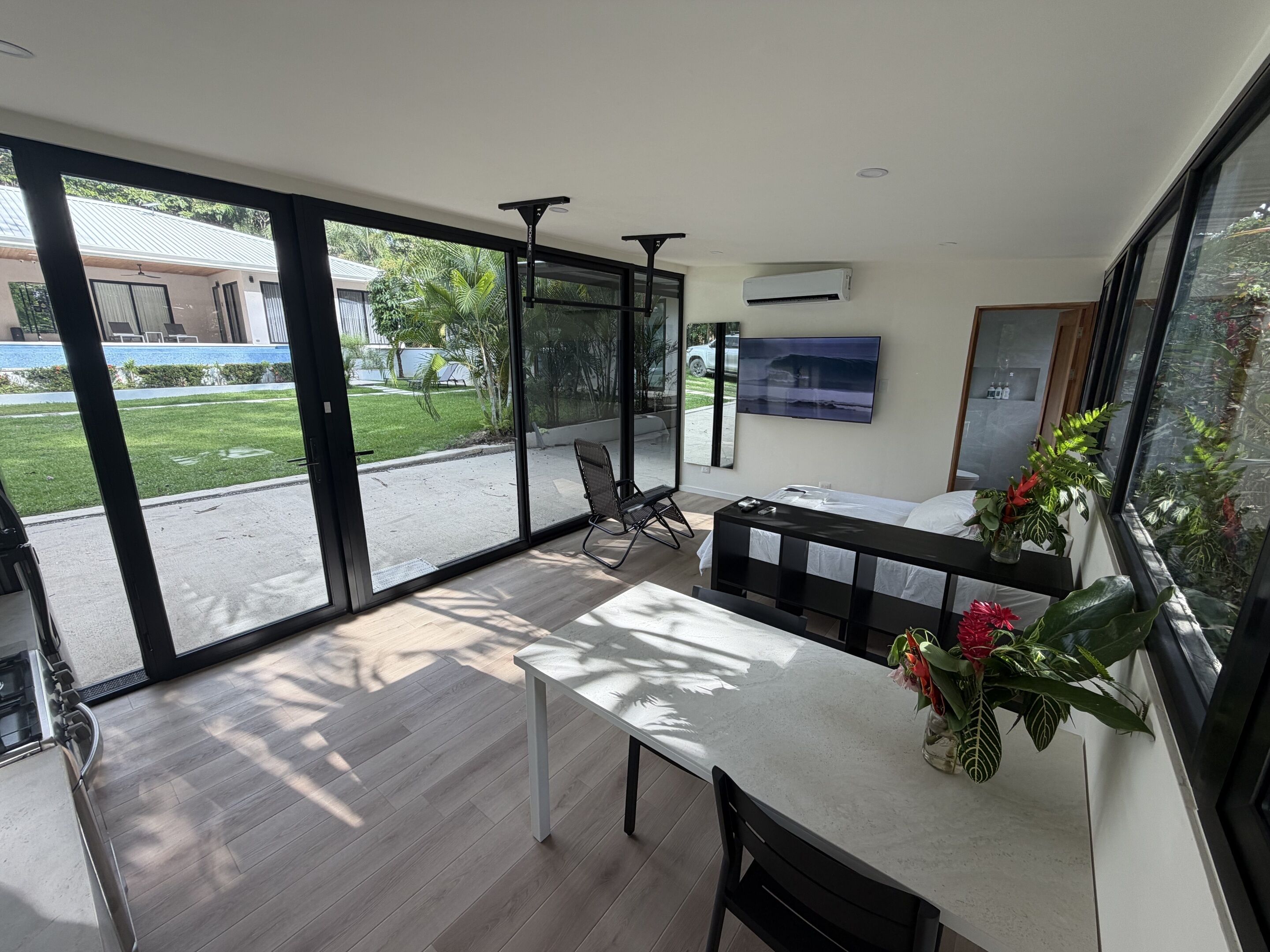 A modern kitchen with a dining area, large sliding glass doors to a patio, and a flat-screen TV mounted on the wall.