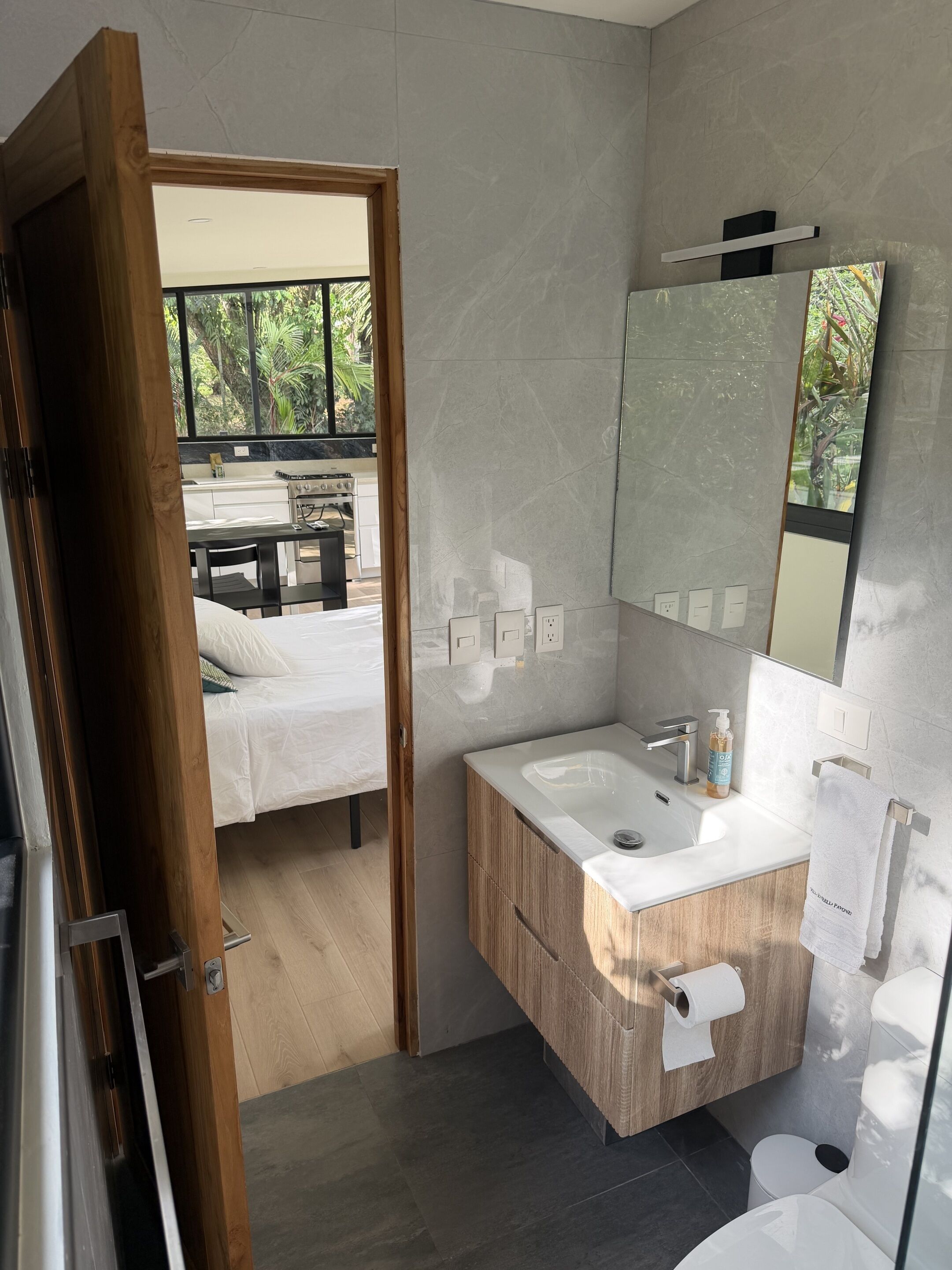 A modern bathroom with a large mirror, wooden vanity, and a toilet.