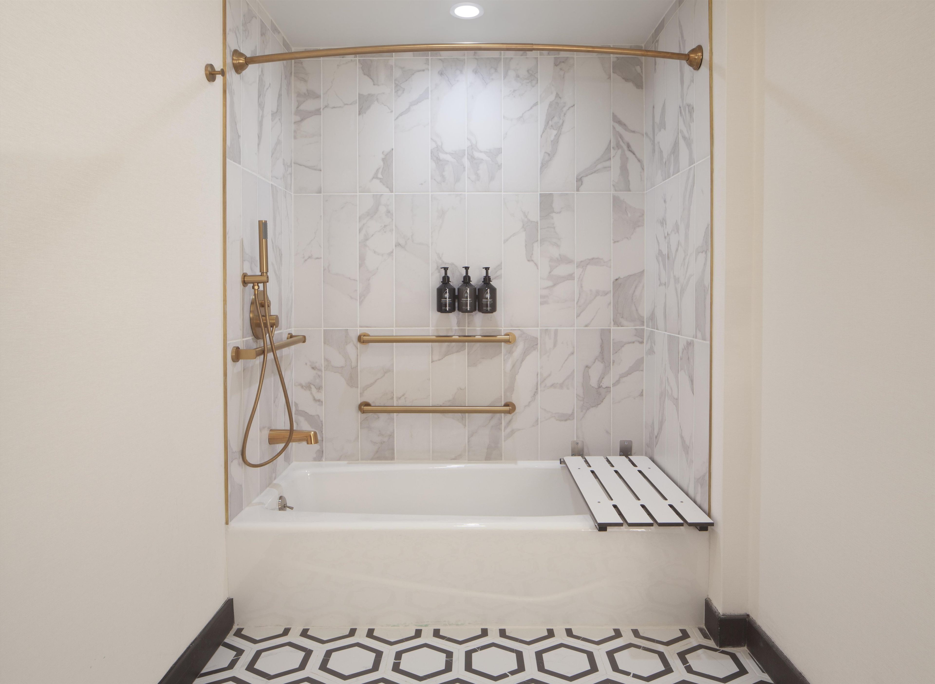 A bathroom with a bathtub, a shower, and a toilet. There are two towel bars and a shelf with toiletries.