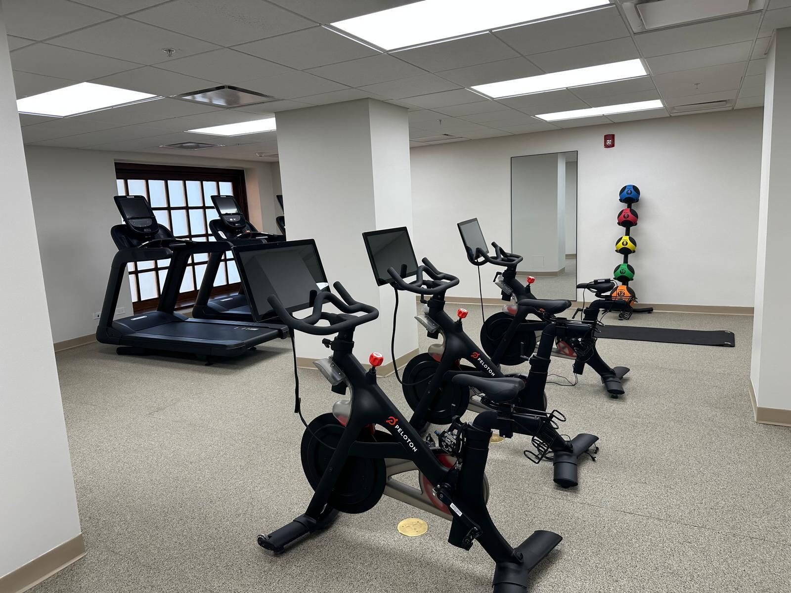 A fitness room with stationary bikes, a treadmill, and exercise mats.