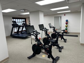 A fitness room with stationary bikes, a treadmill, and exercise mats. - Hotel Royer Urbana Champaign, Tapestry Collection by Hilton (Urbana)