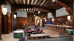 A spacious lobby with a bar area, seating arrangements, and a staircase leading to an upper level.