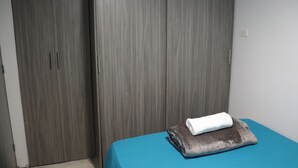 A bedroom with a bed, a grey wardrobe, and a blue bedspread. - Apartahotel Tia Inés (Montenegro)
