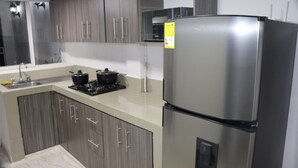 A modern kitchen with grey cabinets, a stainless steel refrigerator, and a gas stove. - Apartahotel Tia Inés (Montenegro)