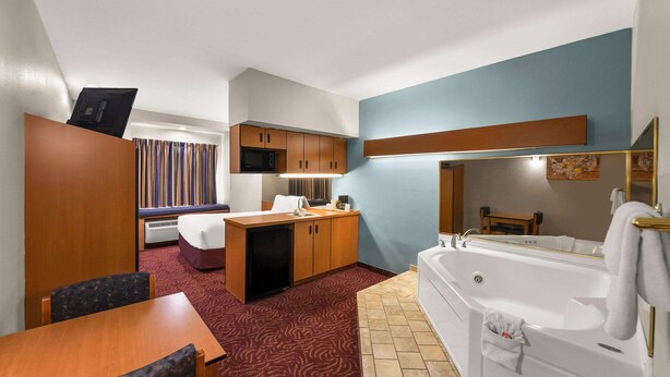 Een compacte hotelkamer met een kitchenette, een eethoek en een badkamer met een bad.