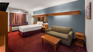 Een hotelkamer met een bed, een bank, een kleintje tafeltje en een nachtkastje.