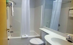 A bathroom with a bathtub, toilet, sink, and a mirror. - Studio 6 Mcalester, Ok - South (McAlester)