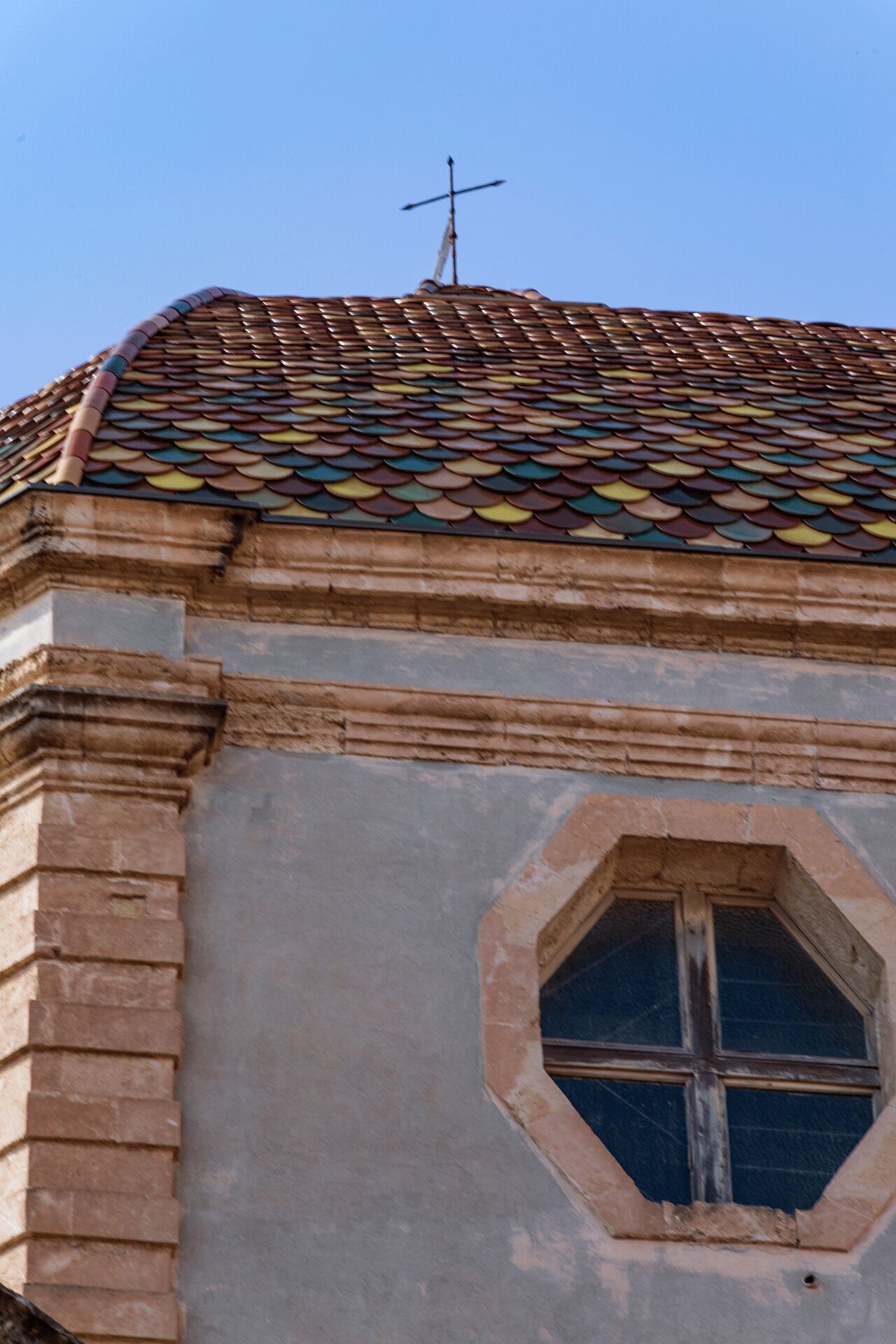 A building with a tiled roof and a cross on top.