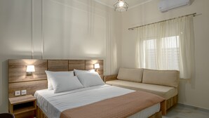 Una camera da letto con un letto, comodini, un divano e una lampada a sospensione.
