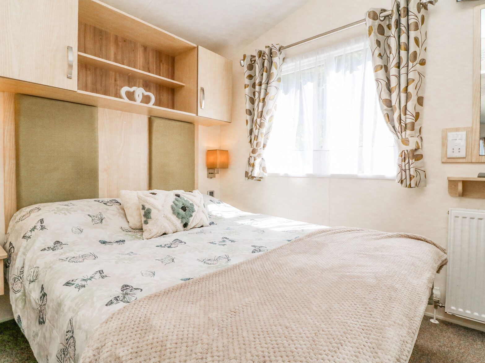 Ein Schlafzimmer mit einem Bett, einem Nachttisch, einer Lampe, einem Kleiderschrank und einem Fenster mit Vorhängen.