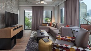 A modern living room with a sofa, coffee table, TV, and a ceiling fan.
