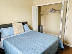 A bedroom with a bed, a wardrobe, and a small storage unit. - Midtown 2BR/2BA Long-Term near Vandy/St.Thomas (Nashville)