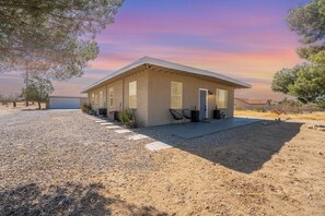 A single-story house with a flat roof, a covered patio, and a gravel driveway.