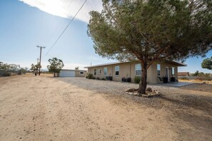 Une maison à deux étages avec une allée en gravier et un arbre devant.