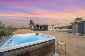 A hot tub in a backyard with a wooden deck, a small shed, and a house in the background. - Desert Escape w/ Hot Tub + Fire Pit | Near Park (Yucca Valley)