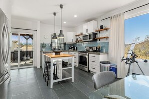 A modern kitchen with a central island, built-in appliances, and a large window offering a view. - Desert Escape w/ Hot Tub + Fire Pit | Near Park (Yucca Valley)