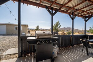 A covered outdoor barbecue area with a grill and seating.