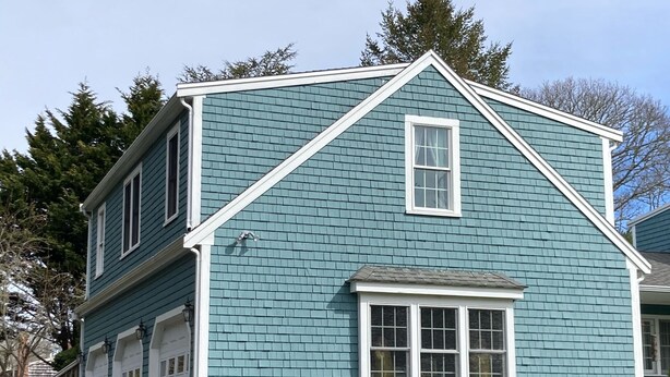 A two-story house with a gabled roof, a garage, and a flower bed in front.