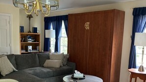 A living room with a sofa, a round coffee table, a bookshelf, and a wooden wardrobe.