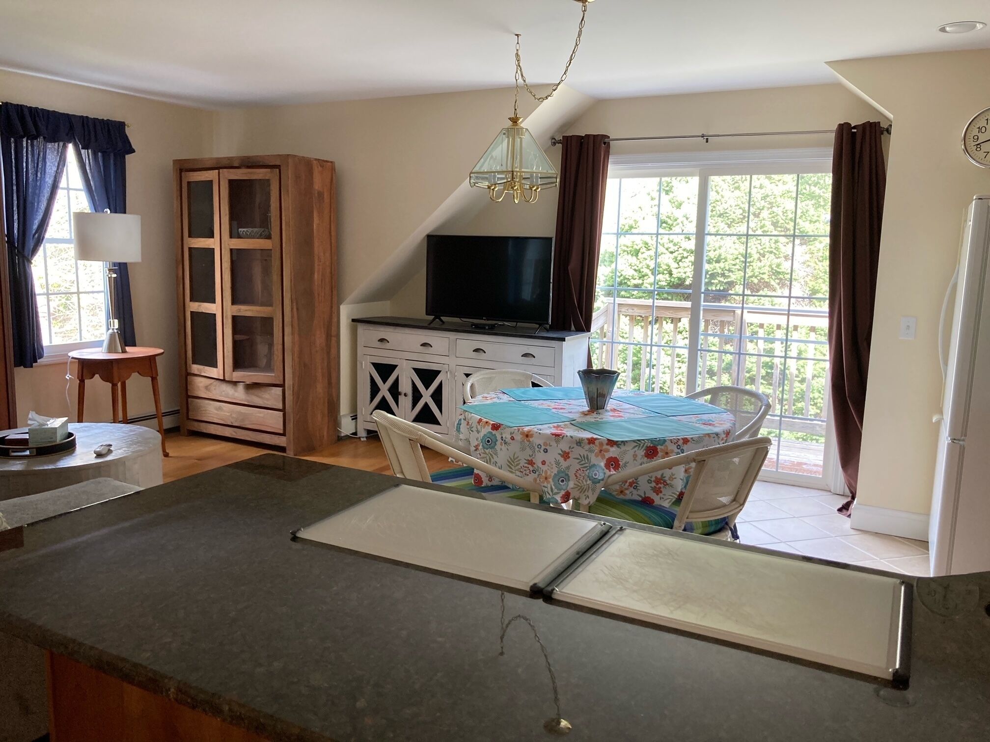 A kitchen with a dining area, a television, and a window with curtains.