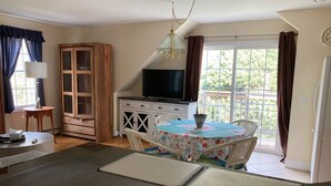 A kitchen with a dining area, a television, and a window with curtains.