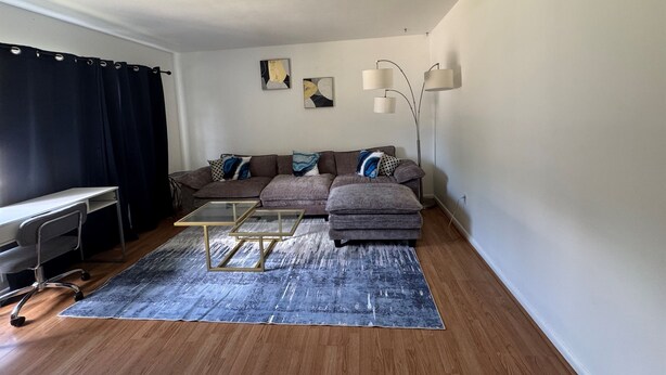 Una sala de estar con sofá, reposapiés, mesa de centro y lámpara de pie.