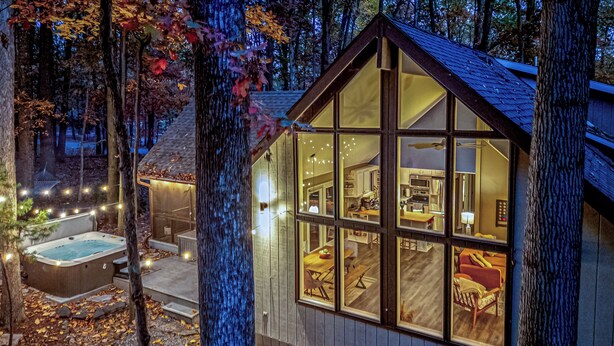 Una cabaña acogedora con un gran ventanal, un jacuzzi y un comedor.
