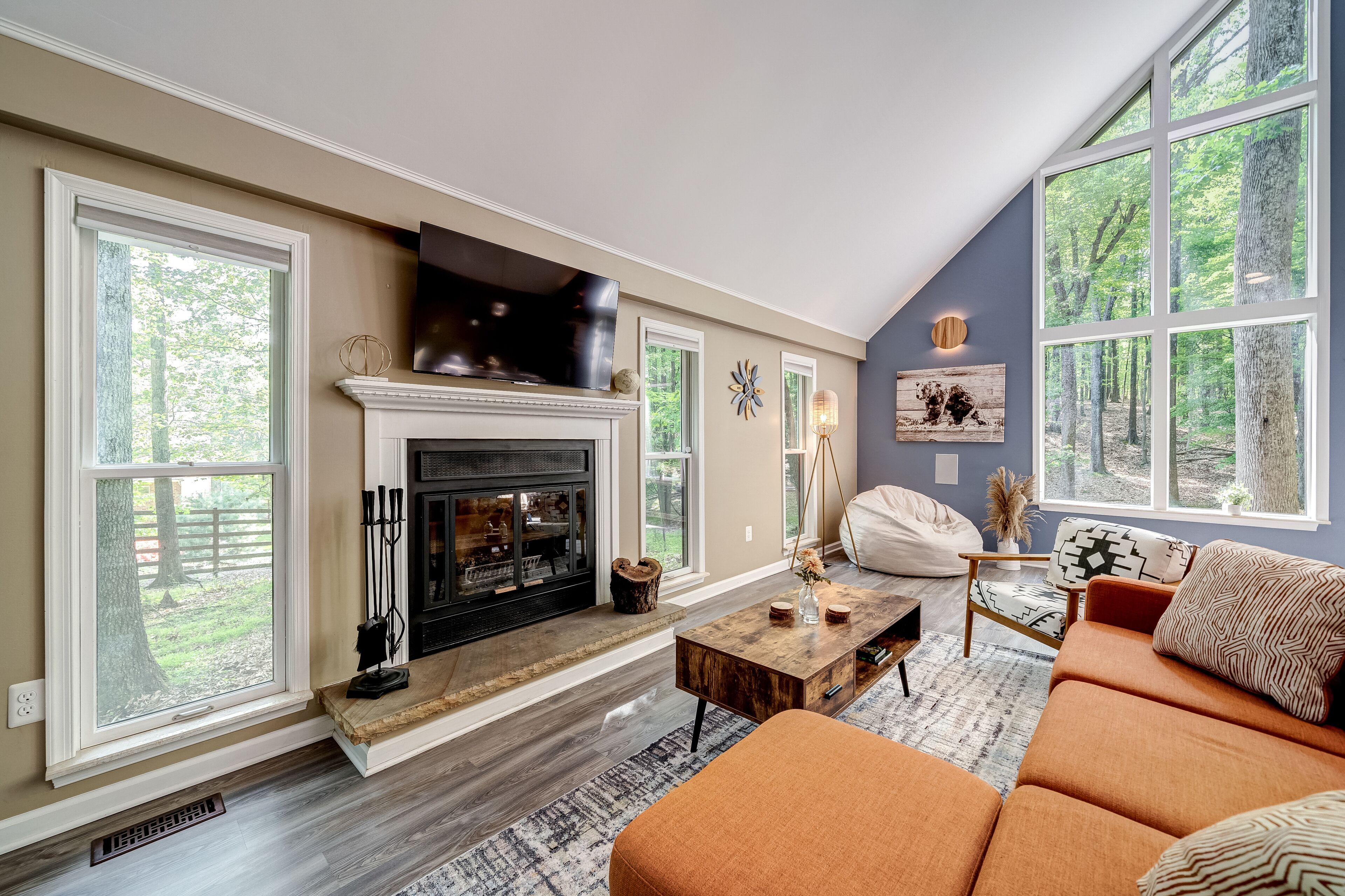 A living room with a fireplace, large windows, a sofa, and a TV.