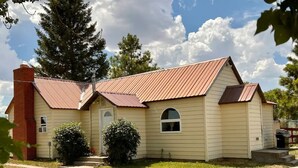 A single-story building with a red roof and beige siding, featuring a front entrance and a small porch area.
