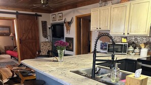 A kitchen with a large island, bar stools, a sink, and a microwave.