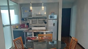 A compact kitchen with a dining table, chairs, and modern appliances.