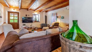 A cozy living room with a wooden ceiling, a television, a fireplace, and a green bottle in a bucket.