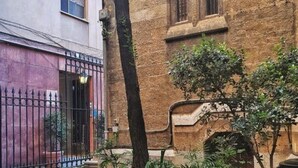 A courtyard with a brick building, a metal gate, and potted plants. - GOLD SUITE&SPA (Palermo)
