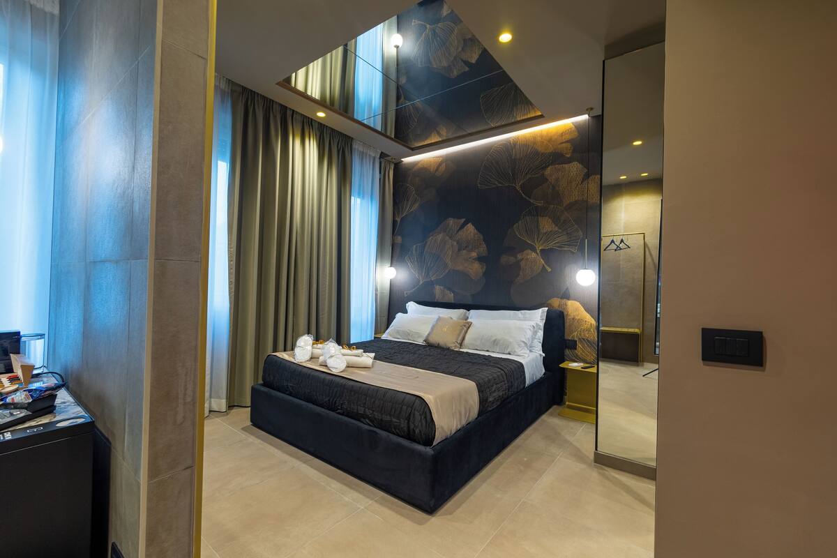 Quarto de hotel moderno com uma cama grande, uma escrivaninha com computador e um espelho.